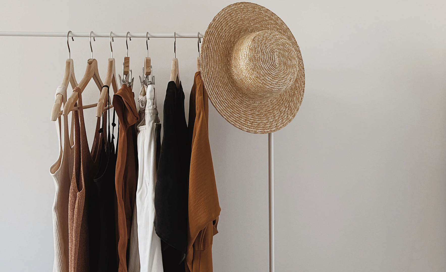 Clothes rack displaying a range of neutral garments (beige, grey, white, black), showing their versatility.